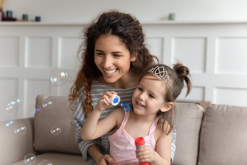 Kind und Babysitter spielen mit Seifenblasen