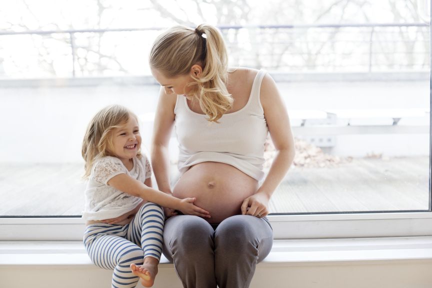 Mädchen berührt den Babybauch ihrer Mutter