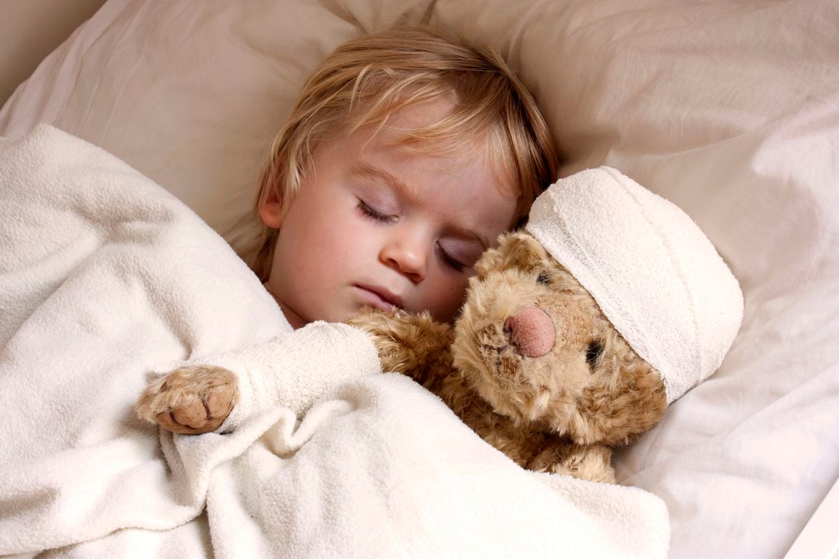 Kind schläft mit Teddy im Arm