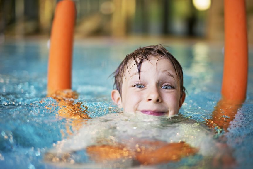 Kind schwimmt mit Poolnudel