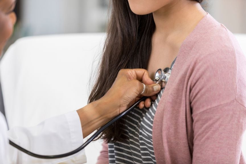 Ärztin hört mit Stethoskop das Herz einer Frau ab