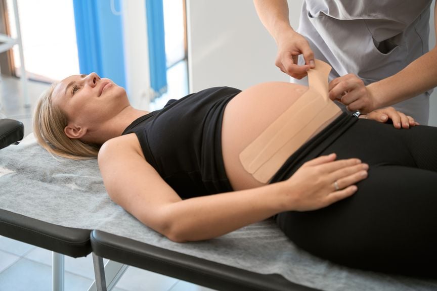 Schwangere bekommt Physio-Tape am Bauch
