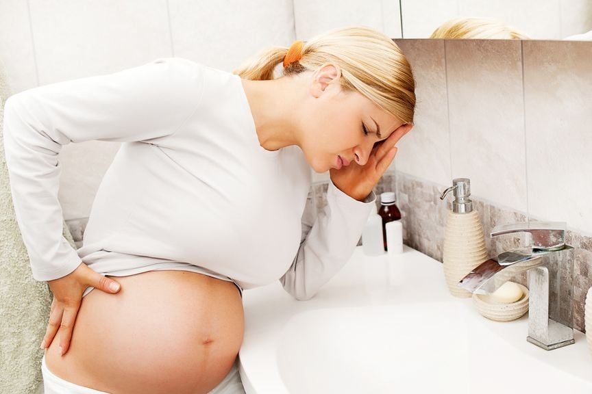 Schwangere mit Schmerzen und Übelkeit am Lavabo