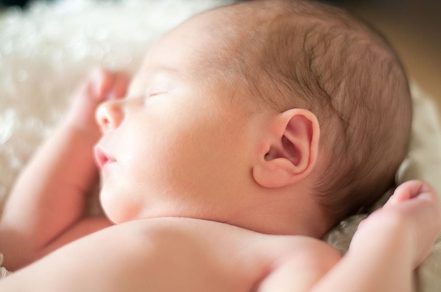 Neugeborenes nackt schlafend auf den Rücken