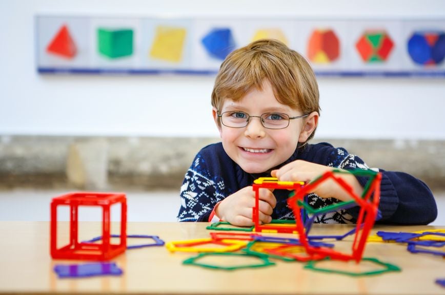 Kind spielt mit farbigen Plastikelementen