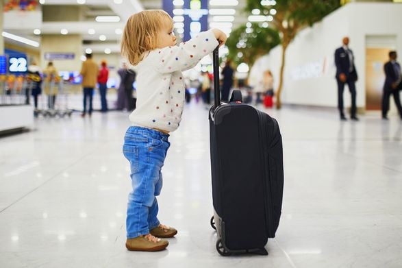 Kind mit Koffer am Flughafen