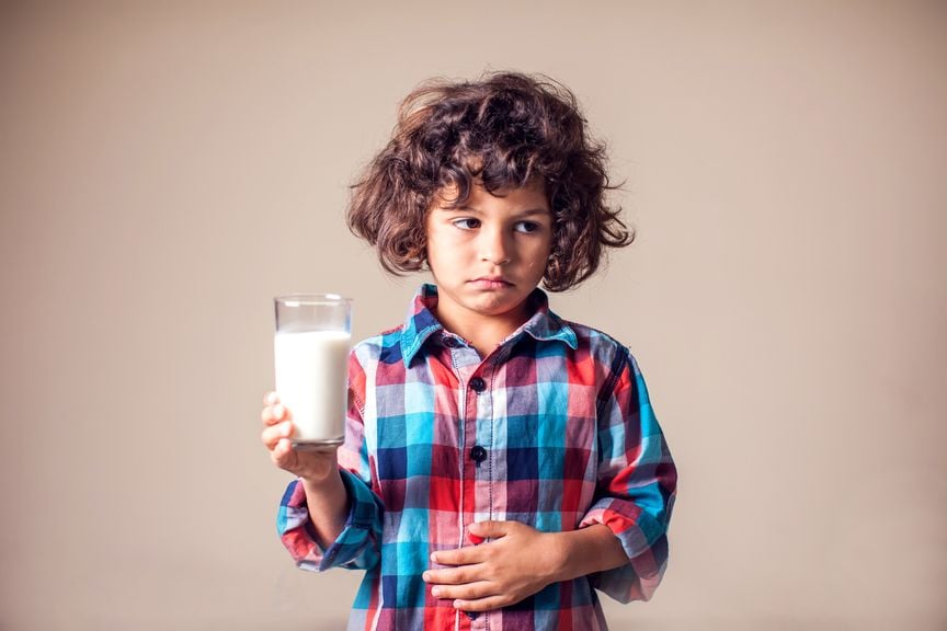 Junge mit einem Glas Milch in der Hand hat Bauchschmerzen