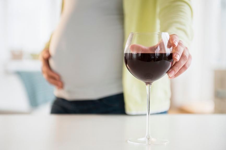 Schwangere greift nach Weinglas
