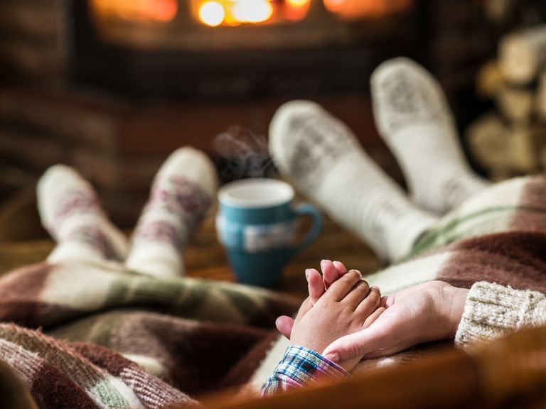 Mutter und Kind halten sich die Hand vor dem Kamin