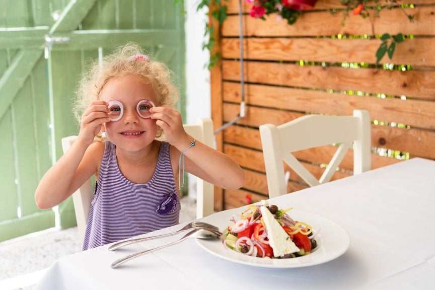 Kind hält Zwiebelringe vor die Augen