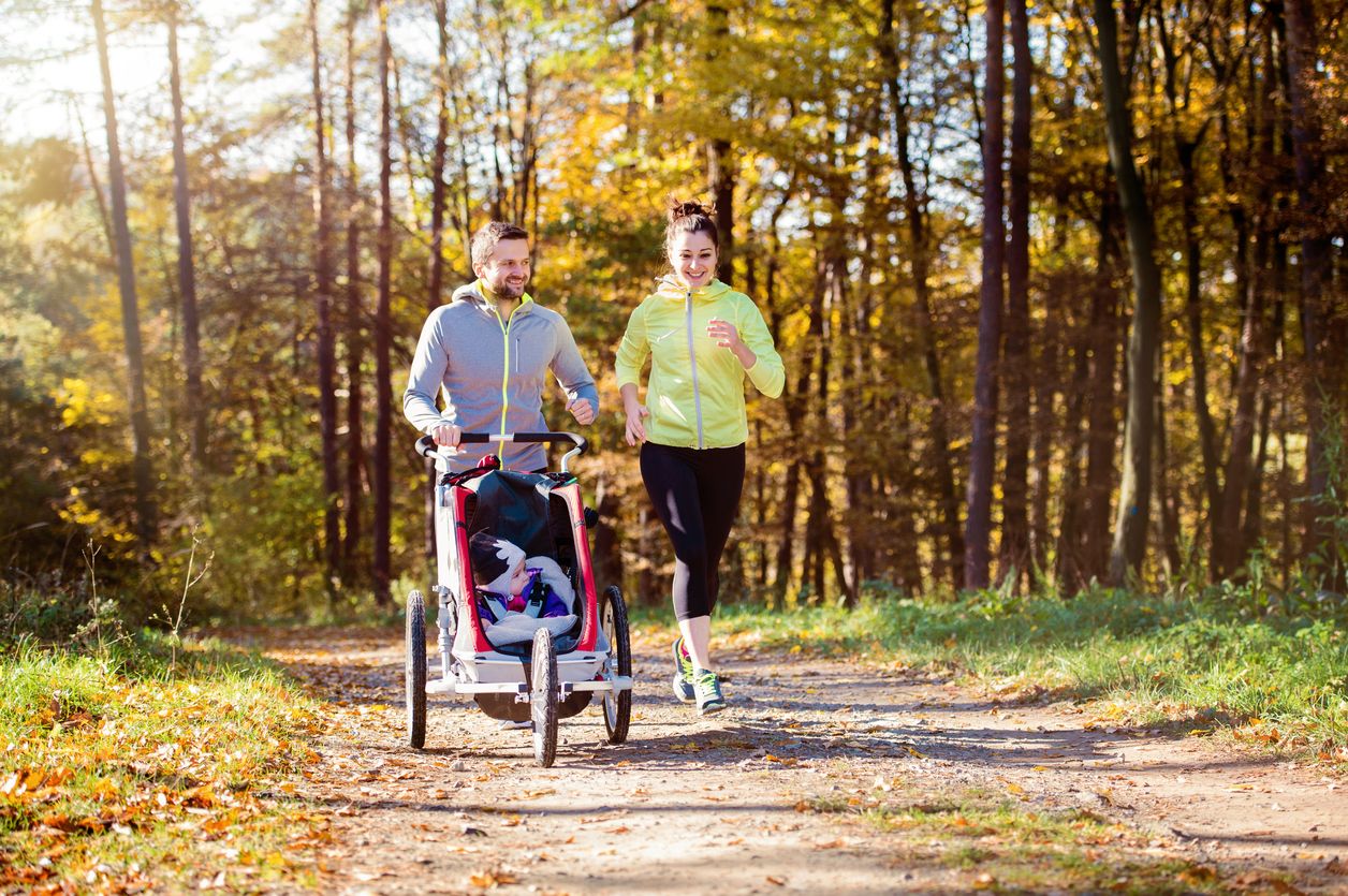 Eltern beim Joggen mit Buggy am Waldrand