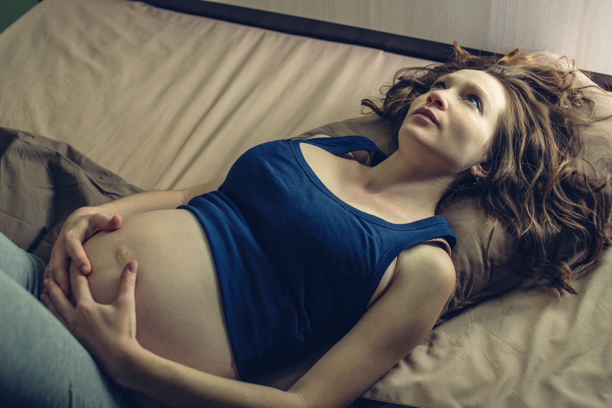 Schwangere liegt wach im Bett