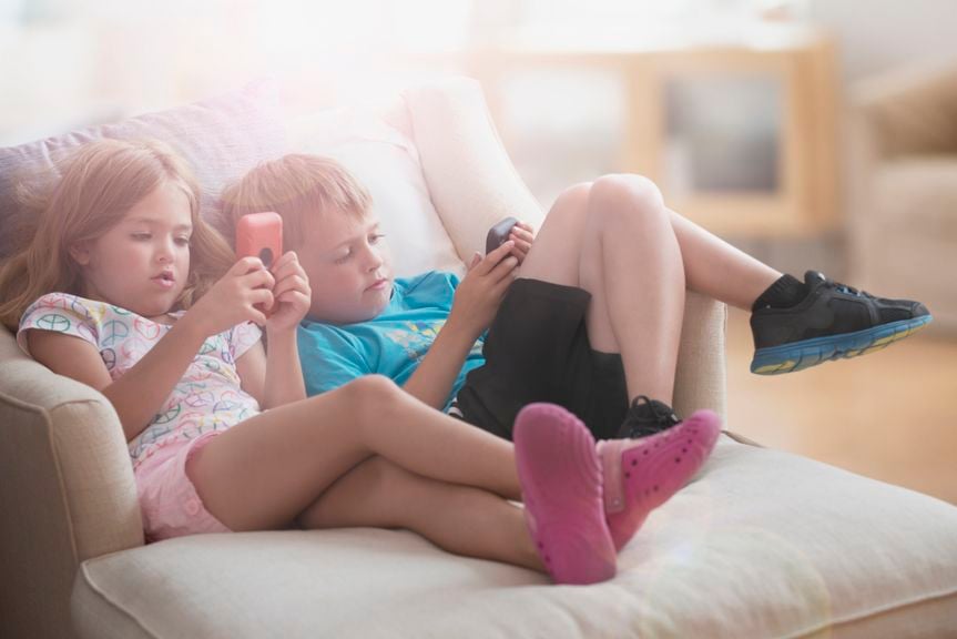 Zwei Kinder auf dem Sofa benutzen ihre Smartphones