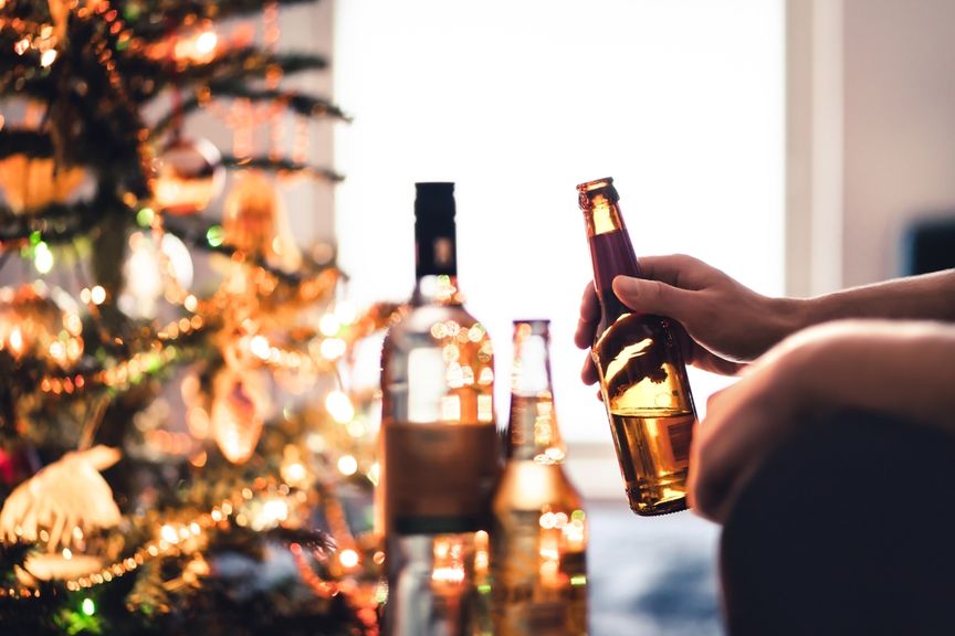 Bier- und Weinflaschen vor einem geschmückten Tannenbaum