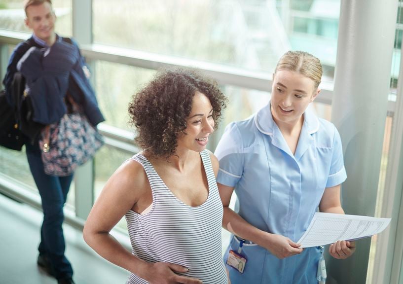 Schwangere ist im Spital eingetroffen und wird von ihrer Hebamme begleitet, ihr Partner folgt im Hintergrund