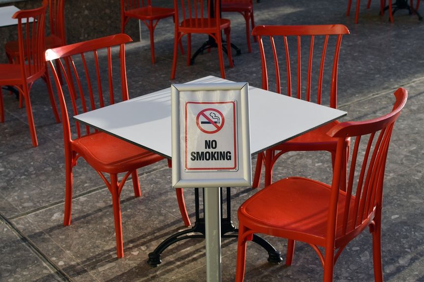 Restauranttisch mit roten Stühlen und einem Rauchverbots-Schild