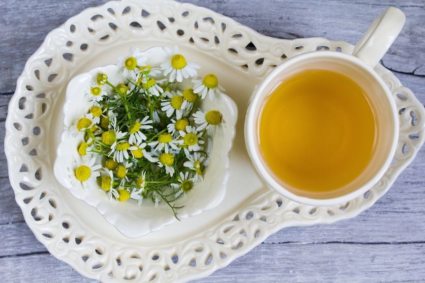 Kamillenblüten und eine Tasse Kamillentee 