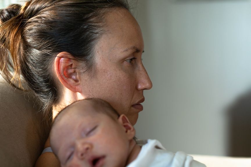 Traurige Mutter hält ihr schlafendes Baby auf dem Arm