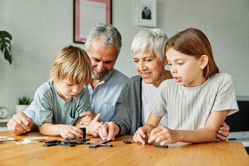 Grosseltern spielen mit zwei Enkeln Domino
