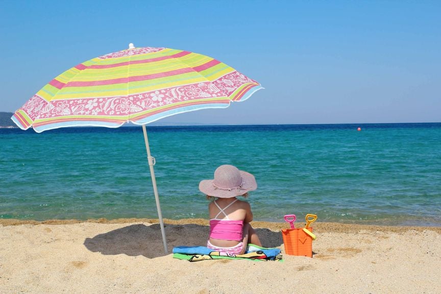 Kind am Strand unter dem Sonnenschirm 