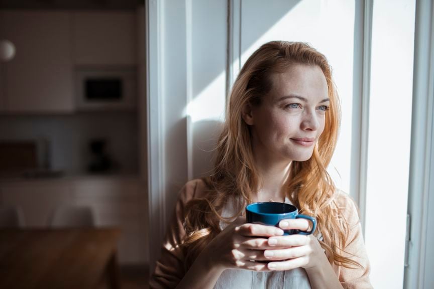  Frau am Fenster mit einer Tasse in der Hand