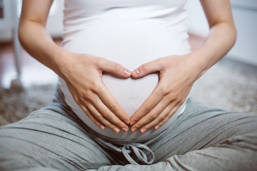 Schwangere bildet mit ihren Händen ein Herz auf ihrem Bauch