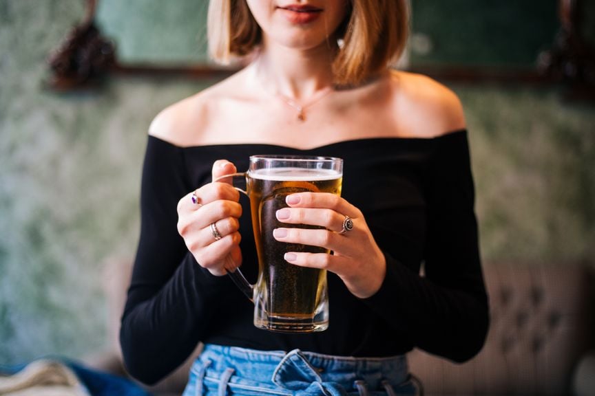 Weiblicher Teenager hält ein grosses Glas Bier in den Händen