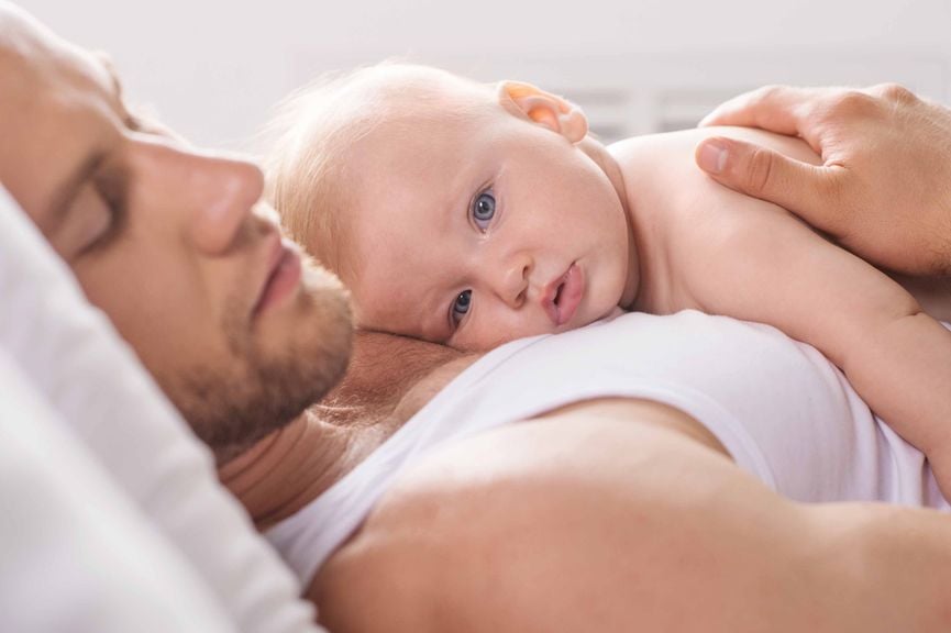 Vater schläft mit Baby auf dem Sofa