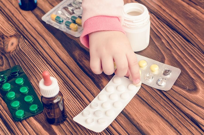 Babyhand greift nach diversen Medikamenten auf dem Tisch