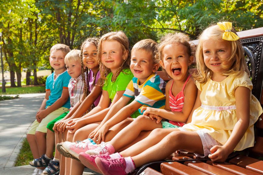 Kindergartenkinder machen Pause auf Parkbank