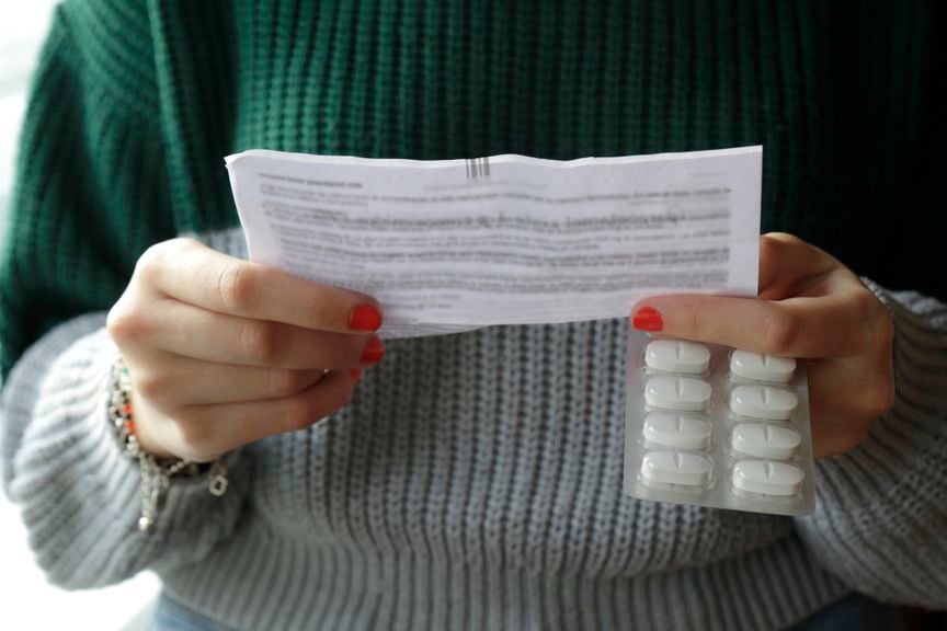 Frau mit Tablettenpackung liest Packungssbeilage 
