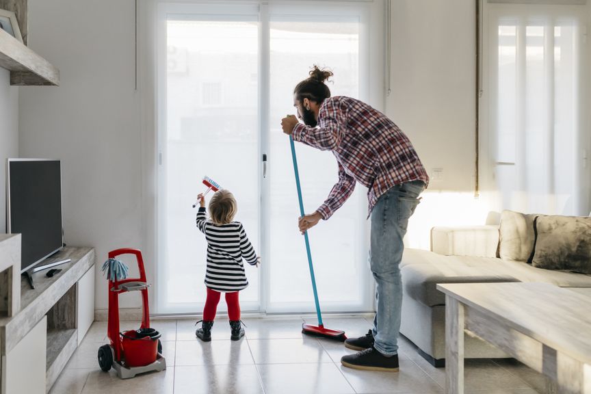 Vater und Kleinkind putzen gemeinsam die Wohnung