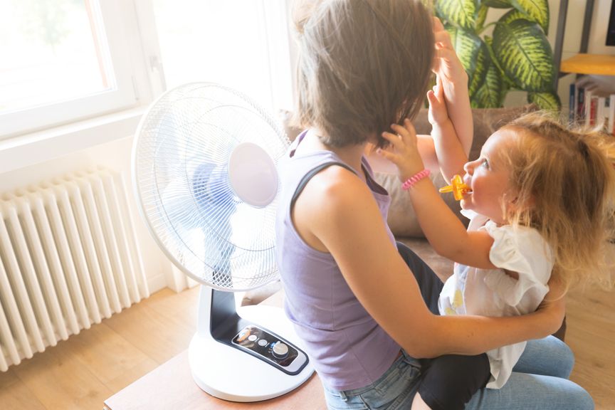 Frau mit Kind sitzt vor dem Ventilator