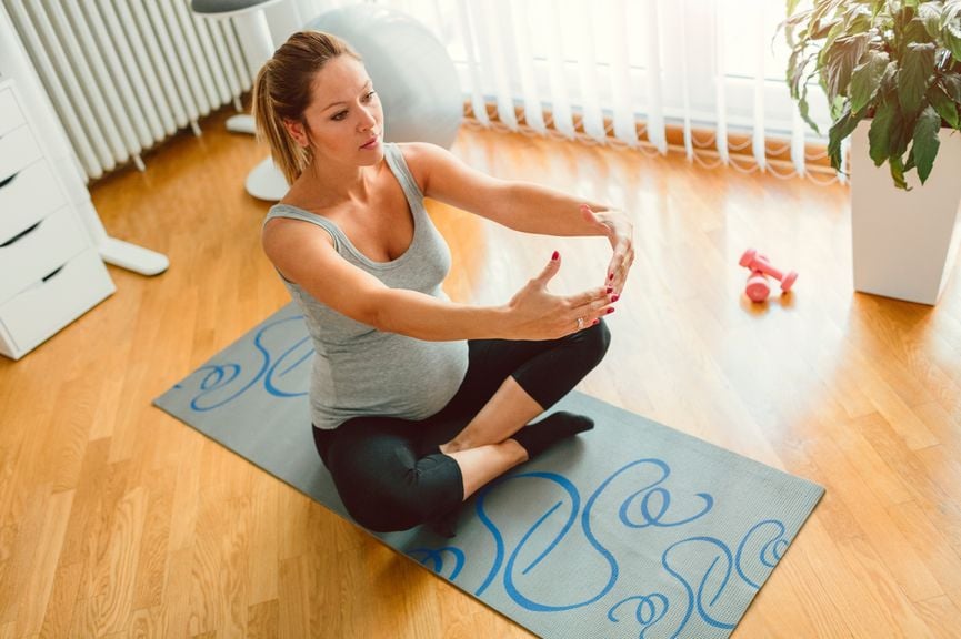 Schwangere macht Yoga Übungen zu Hause