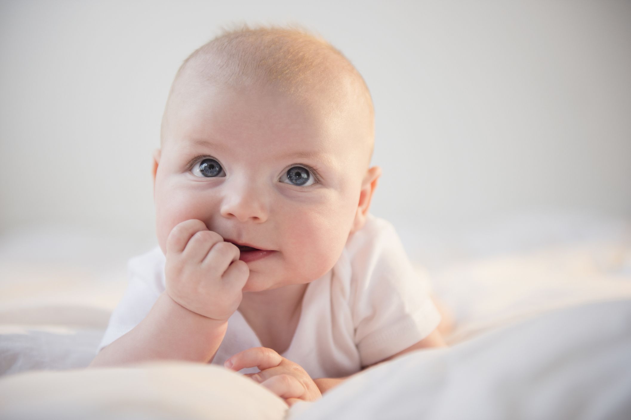 Baby auf dem Bauch mit der Hand im Mund