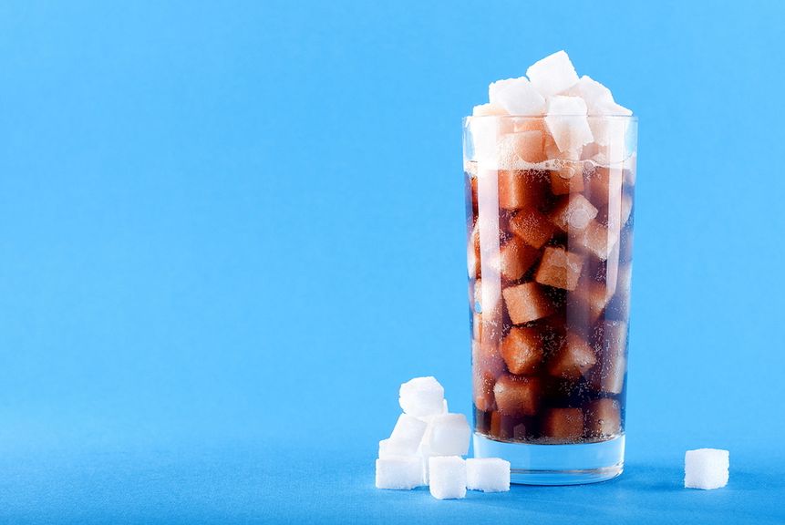 Trinkglas gefüllt mit Zuckerwürfeln und Colagetränk
