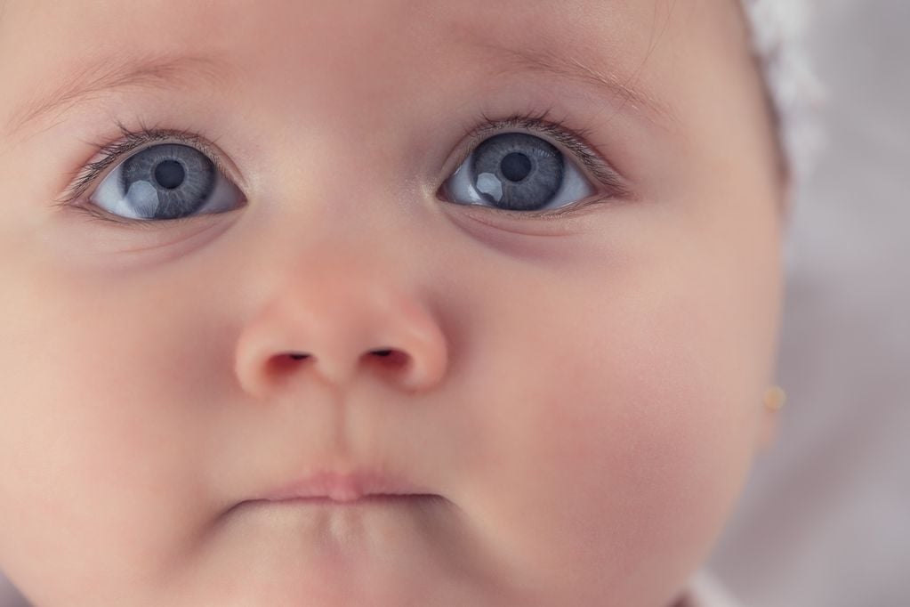 Babygesicht mit riesigen blauen Augen und Kappe
