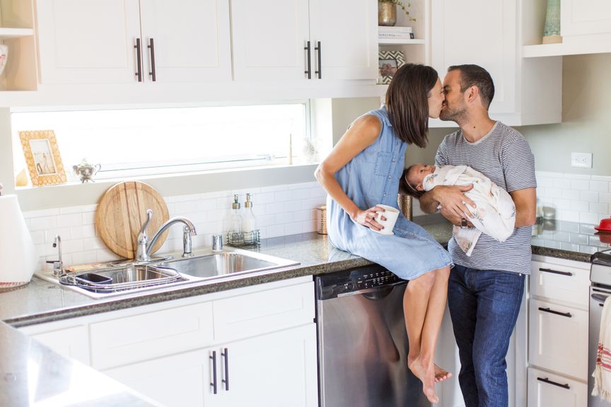 Paar mit Baby küsst sich in der Küche