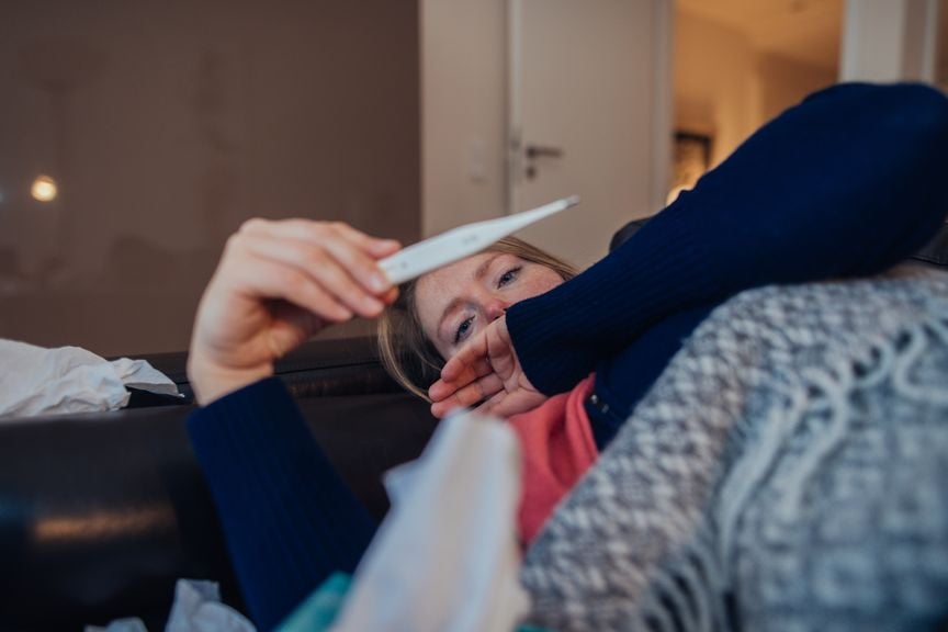 Frau betrachtet das Fieberthermometer