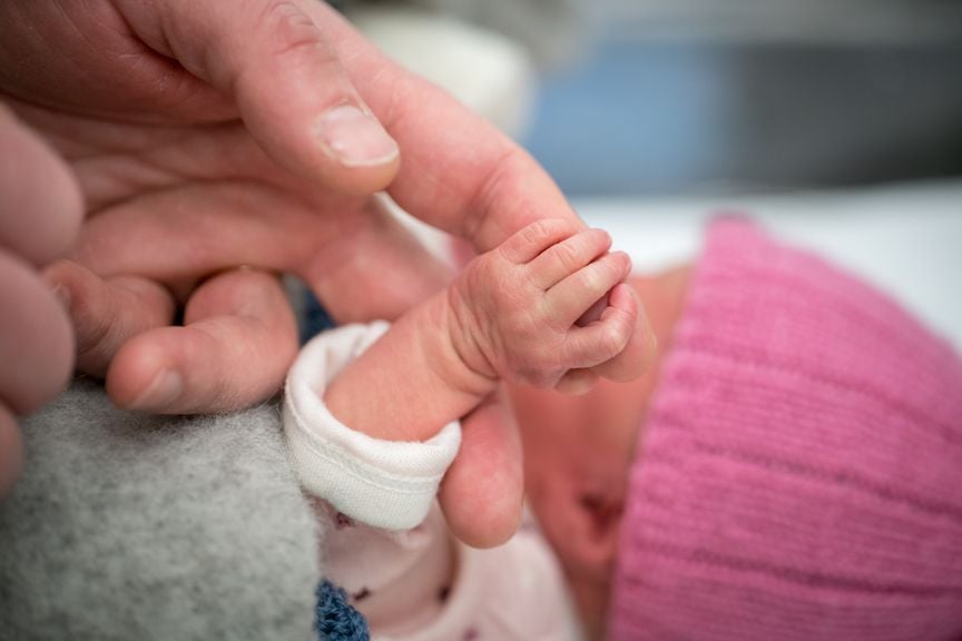 Hand des Frühgeborenen hält Erwachsenenfinger