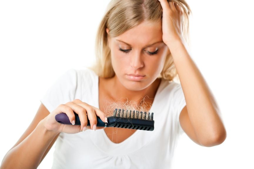 Frau rauft sich die Haare und schaut auf die Haarbürste