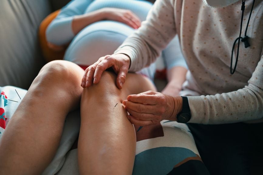 Schwangere Frau bekommt während einer Akupunkturbehandlung an den Beinen