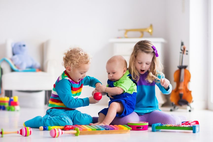 Kinder spielen mit Musikinstrumenten am Boden