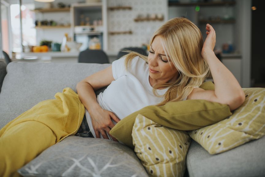 Frau auf dem Sofa mit Bauchschmerzen