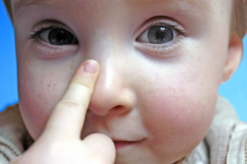 Kind mit Zeigefinger auf der Nase