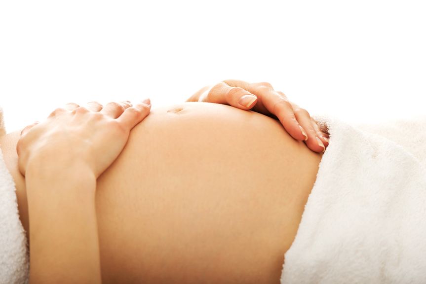 Schwangere streicht sich liegend über den Bauch