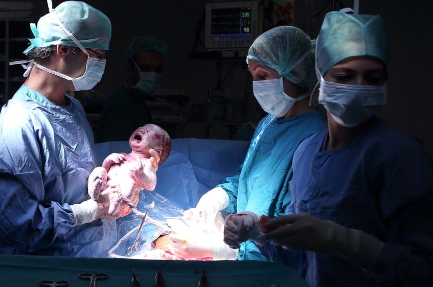 Arzt hält Baby nach Kaiserschnitt