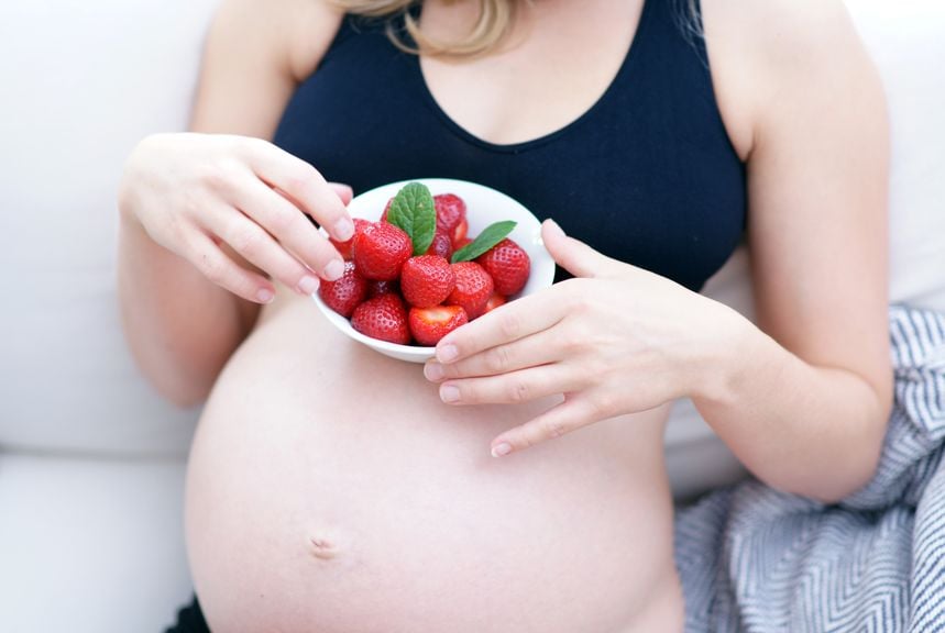 Fragen zur Ernährung,Schwangere mit nacktem Bauch und Erdbeeren