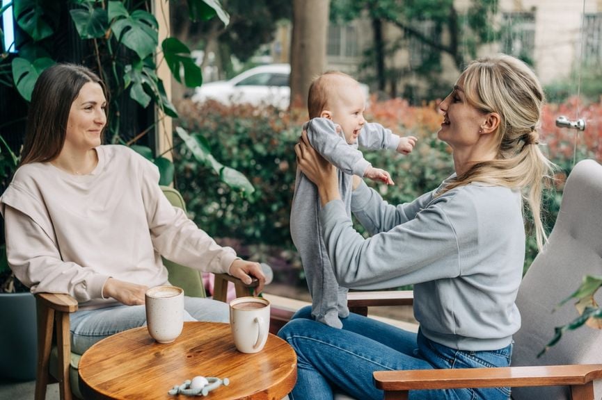 Zwei Frauen mit einem Baby beim Kaffeetrinken