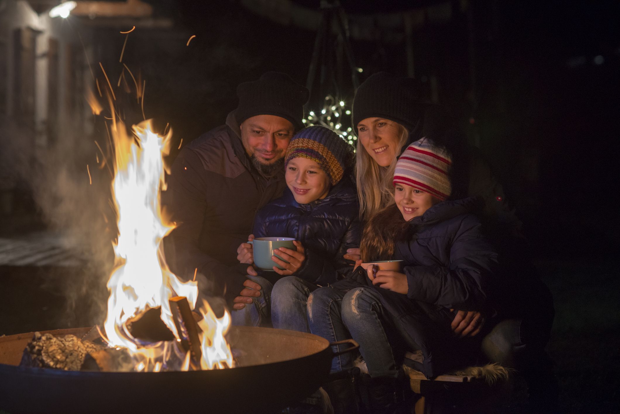 Familie sitzt im Dunkeln am Lagerfeuer